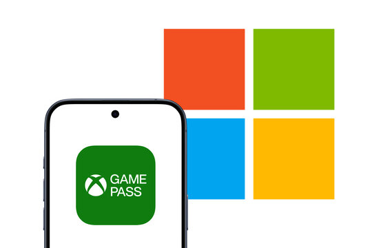 xBox Game Pass logo is displayed on a smartphone, Microsoft behind it, Game Pass is a subscription service as part of Xbox and offered by Microsoft Gaming, console, computer, video games