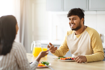 Cheerful millennial indian man have breakfast with his girlfriend