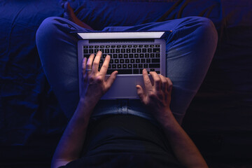 Close up of hacker hand stealing data, man networking on laptop late at night.