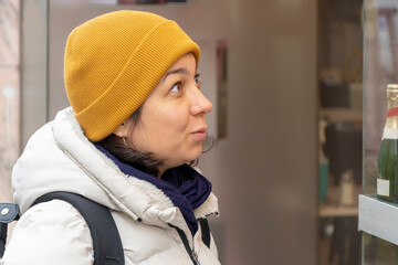A 40-45 year old woman looks at a street window, a look of surprise on her face.