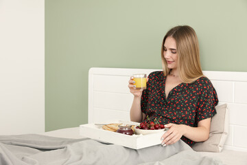 Young woman having breakfast in bed - 762385575