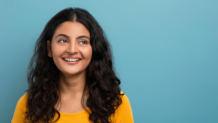 Smiling woman in yellow top on blue background