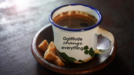 Life inspirational quote - Gratitude change everything. Grateful text concept on a traditional cup of black coffee and brown sugar on ceramic plate on the wooden table.