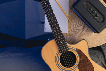 Musical background with acoustic guitar, speaker and notepad on the table.
