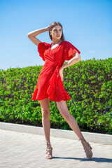 Portrait of a young beautiful brunette woman in a short red dress