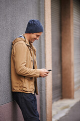 Happy, typing and man in city with phone for social media, networking and online text message in street. Travel, weekend and person on cellphone for website, internet search and chat in urban town