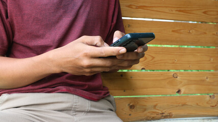 A man sits and types a message using a hand phone or smart phone. Social life in the age of...