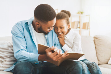 Cute girl and loving father enjoying time together, reading book