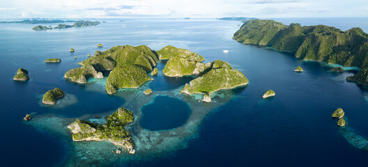 Beautiful limestone islands rise from Raja Ampat's tropical seascape. This region of Indonesia is...