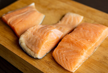  Close-up of raw, fresh salmon fillets arranged neatly on a wooden cutting board, showcasing their vibrant colors and textures