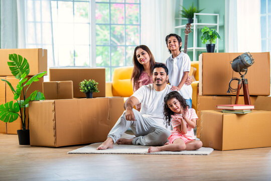 Happy Indian family unpacking boxes at new home