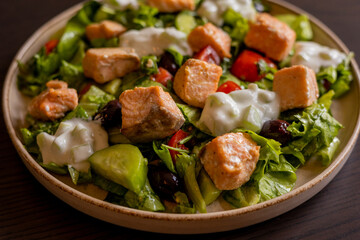 Close-up of a delicious Mediterranean salad featuring pieces of salmon fillet and a dollop of...