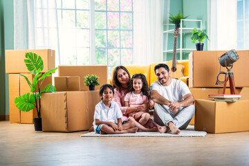 Happy Indian family unpacking boxes at new home - obrazy, fototapety, plakaty
