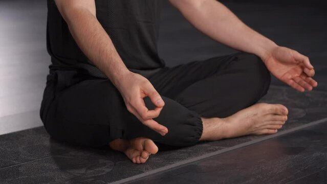 Close-up of a man demonstrating the connection between breathing practices and emotional regulation. man in lotus position, face not visible