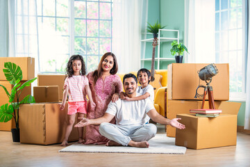 Happy Indian family unpacking boxes at new home - obrazy, fototapety, plakaty