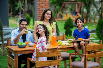 Indian couple and kids Enjoying Family Meal in the garden dining table