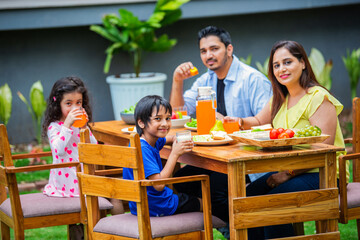 Indian couple and kids Enjoying Family Meal in the garden dining table