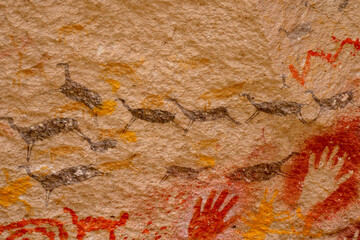 Close up of colourful animal rockpaintings of llamas and handprints on rock walls at Cueva de las Manos, UNESCO World Heritage Site, Patagonia, Argentina