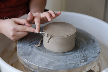 Close up of hands trimming ceramics on a pottery wheel.