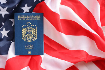 Blue United Arab Emirates passport on United States national flag background close up. Tourism and...
