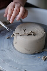 Vertical: Close up of a potter trimming ceramics on a pottery wheel.