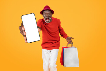 An ecstatic senior black man in a red sweater and hat, presenting a blank smartphone screen - obrazy, fototapety, plakaty