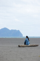 Woman sit on the beach and look at the Guishan at Yilan - 762413303