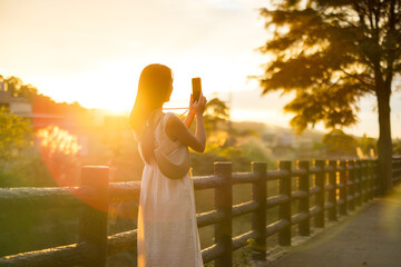Woman take photo on cellphone under sun flare in the countryside - 762413555