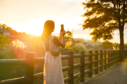 Woman take photo on cellphone under sun flare in the countryside