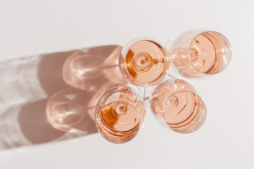 Rose wine glasses Minimal style above view, peach fuzz trend color. Holiday aesthetic still life photo, top view wineglass at natural light, sun shadows, pink pastel color, simple drink background