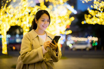 Woman hold with smart phone in Taipei city at night