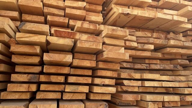 Stacked Timber Planks at a Lumberyard Awaiting Transportation. Stacked wooden planks in varying shades of brown at a timber storage facility.