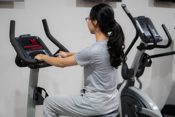 Woman using elliptical cross trainer in gym modern fitness center room