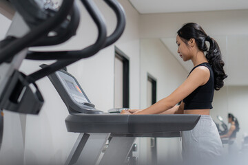 Woman using elliptical cross trainer in gym modern fitness center room
