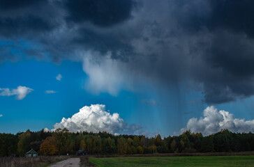 Short rain on the outskirts of the village. Structured clouds. Old Lithuanian building