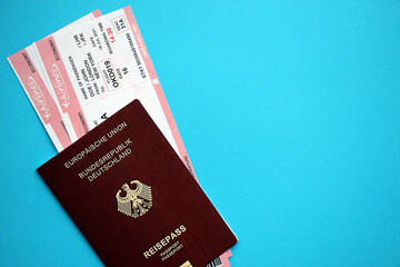 Red German passport of European Union with airline tickets on blue background close up. Tourism and travel concept