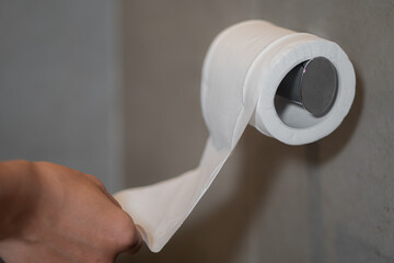 Hand using toilet paper roll