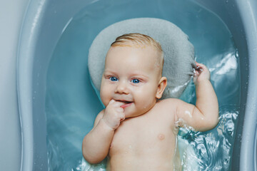 Hygiene of newborns and children. The baby lies on a stand and bathes in a bathtub. Bathing a newborn baby in a bath