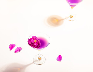 Cold purple violet exotic cocktail in glasses with decorated flowers and petals.