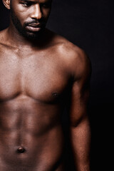 Fototapeta na wymiar Black man, stomach and beauty on a dark background for dermatology and shadow or light with art deco or aesthetic. Cosmetics model or young person thinking in studio with shirtless abs and fitness