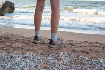 Male feet in sneakers on the sandy seashore. Travel and tourism.