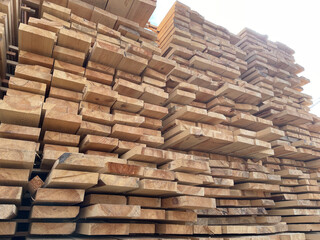 Stacked Timber Planks at a Lumberyard Awaiting Transportation. Stacked wooden planks in varying shades of brown at a timber storage facility.