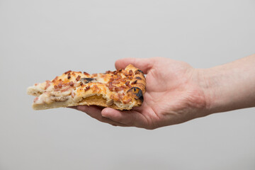 A Caucasian man holds a slice of pizza in a hand.