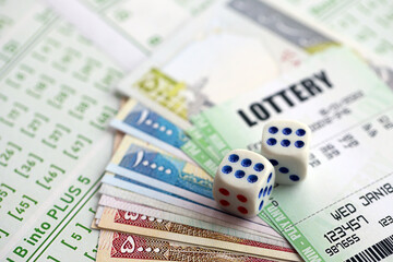 Green lottery tickets and iranian money bills on blank with numbers for playing lottery close up