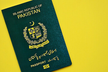 Green Islamic Republic of Pakistan passport on yellow background close up. Tourism and citizenship concept