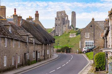 Corfe Castle ruins in Dorset on a sunny summer’s day with traditional Portland stone cottages...