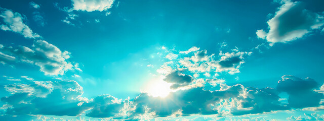 Fototapeta na wymiar A blue sky with a few clouds and the sun shining through them