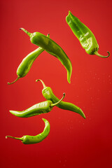Green chilies in the air, food vegetable advertisement, product photography with a bright red background