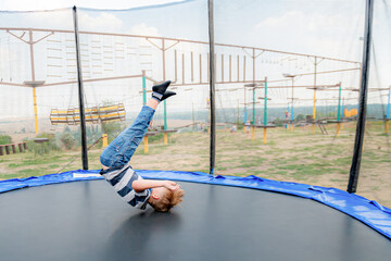 Boy does a somersault jumping on a trampoline in a sports extreme park.