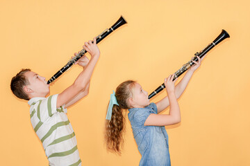 Boy and girl musicians playing the clarinet, on a yellow background.